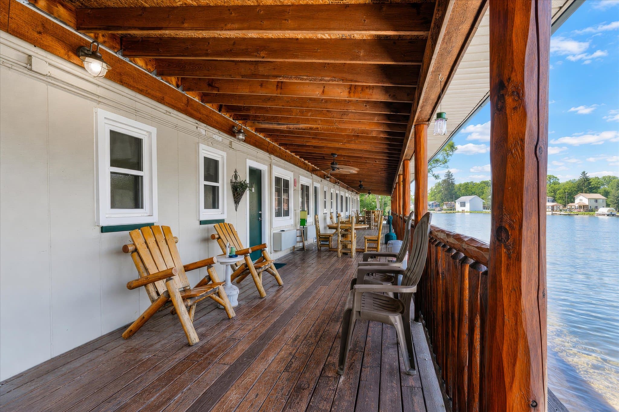Covered lakeside deck with log chairs overlooking the water at Olde Mill Inn of Clarkston